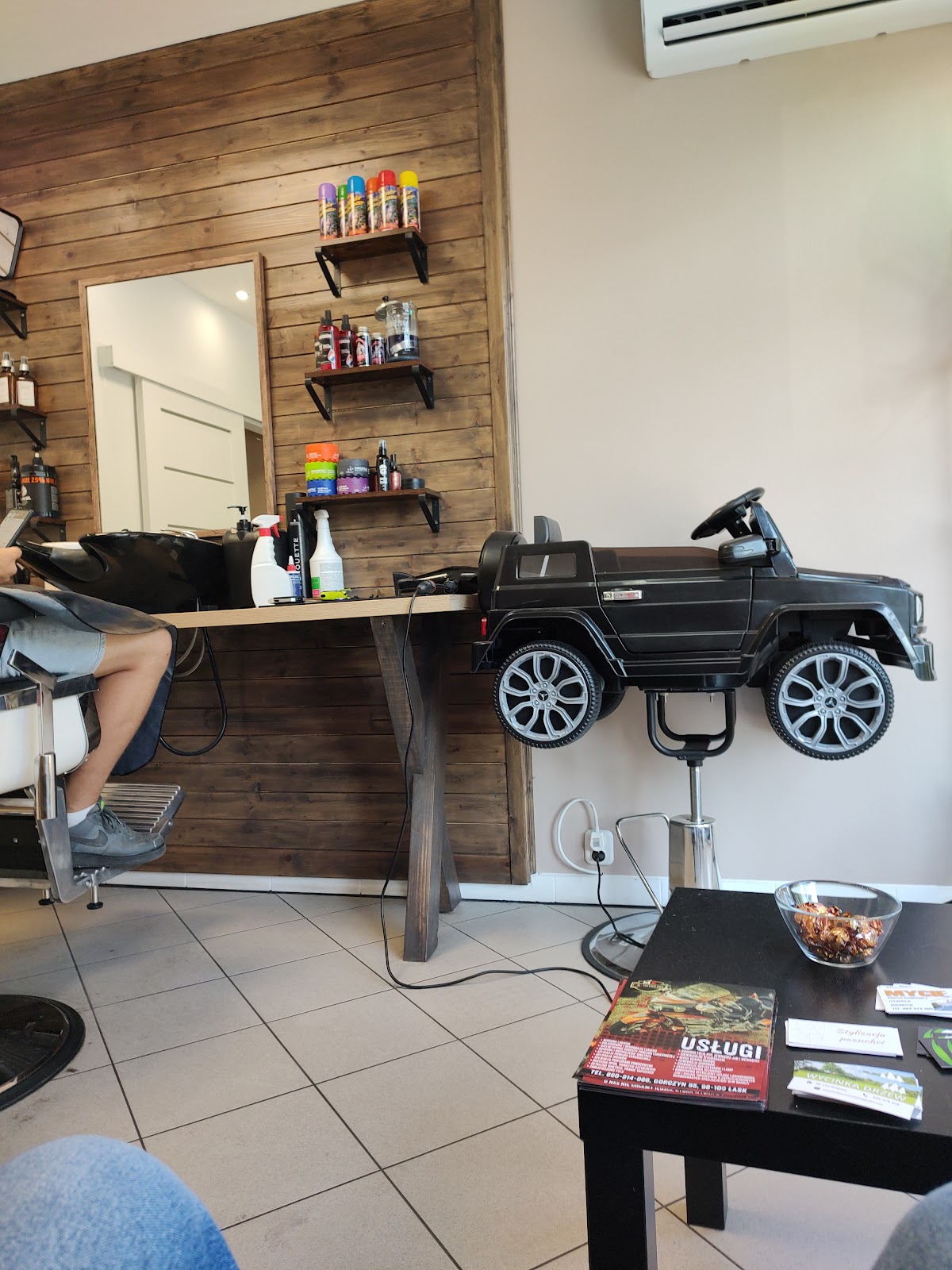 Wnętrze Barber Mieszko, drewniana ściana, lustro i stanowisko barberskie